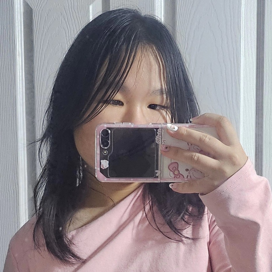 A mirror picture of a girl with dark hair wearing a pink long-sleeved top